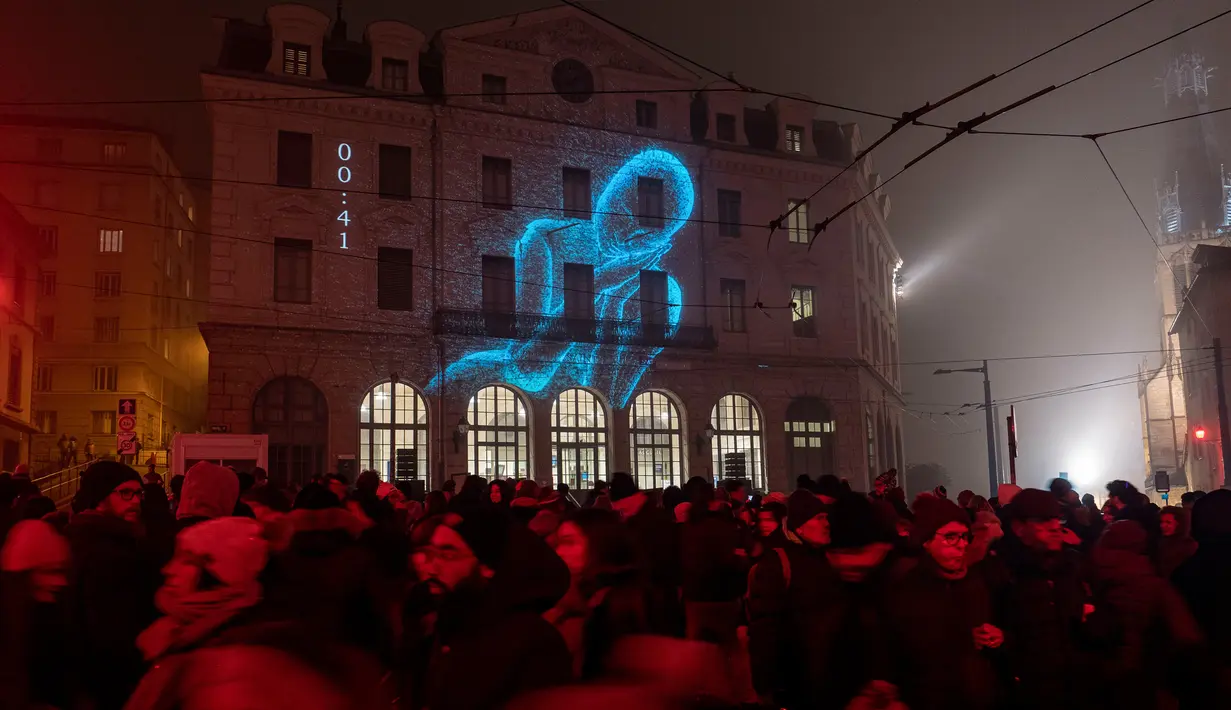Orang-orang berjalan di sebelah stasiun kereta api Lyon-Saint-Paul yang diterangi cahaya lampu selama Festival of Lights (Fete des Lumieres) di kota Lyon, Prancis, Kamis (5/12/2019). Festival Cahaya ini merupakan salah satu kegiatan yang paling terkenal di Lyon. (ROMAIN LAFABREGUE / AFP)