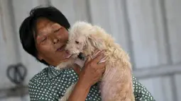 Yang Xiaoyun bermain dengan seekor anjing di tempat penampungannya di Tianjin, China, Rabu (8/7). Yang Xiaoyun dikabarkan telah mengeluarkan uang sebesar 48.248 USD untuk menyelamatkan 500 anjing dari toko daging anjing (REUTERS/Kim Kyung-Hoon)