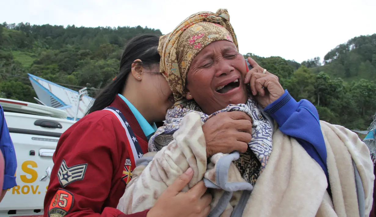 Dua wanita menangis saat mengetahui keluarganya menjadi korban hilang KM Sinar Bangun yang tenggelam di Danau Toba, Sumatera Utara, Selasa (19/6). Dugaan sementara penyebab kapal karam akibat kelebihan muatan. (AFP Photo/Lazuardy Fahmi)