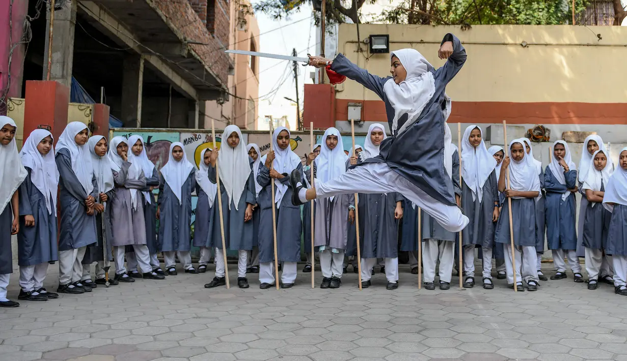 Seorang gadis muslim (tengah) memainkan pedang saat berlatih seni bela diri Vovinam untuk tampil dalam Hari Perempuan Internasional di sekolah menengah St Maaz, Hyderabad, India, Kamis (5/3/2020). Vovinam adalah seni bela diri menggunakan pedang dan tongkat asal Vietnam. (NOAH SEELAM/AFP)
