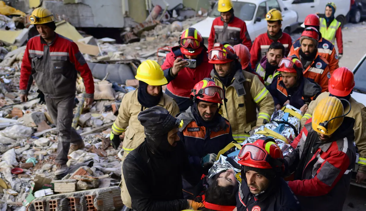 Tim penyelamat mengevakuasi seorang gadis Suriah berusia 12 tahun, Cudi, dari puing-puing bangunan yang hancur di Hatay, Turki, setelah gempa berkekuatan 7,8 melanda tenggara negara itu, Minggu (12/2/2023). Tim penolong mulai kelelahan mencari korban selamat di puing-puing akinbat gempa Turki dan Suriah, ketika korban tewas sudah mencapai 28.000 dan tampaknya akan terus bertambah. (Photo by Yasin AKGUL / AFP)