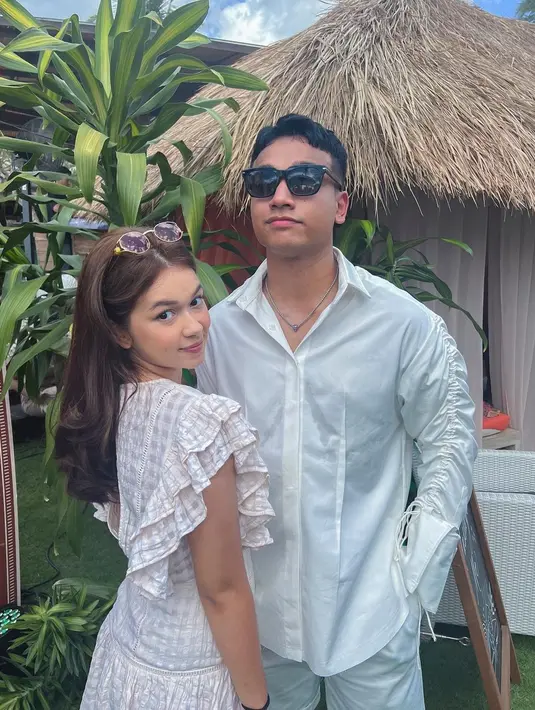 <p>ompak mengenakan outfit serba putih, Fadly dan Rebecca tampil serasi. Fadly memilih mengenakan kemeja putih dengan detail kerut di sepanjang lengan panjangnya, sedangkan Rebecca memilih mengenakan dress kotak-kotak putih dengan detail lengan pendek ruffles. Foto: Instagram.</p>