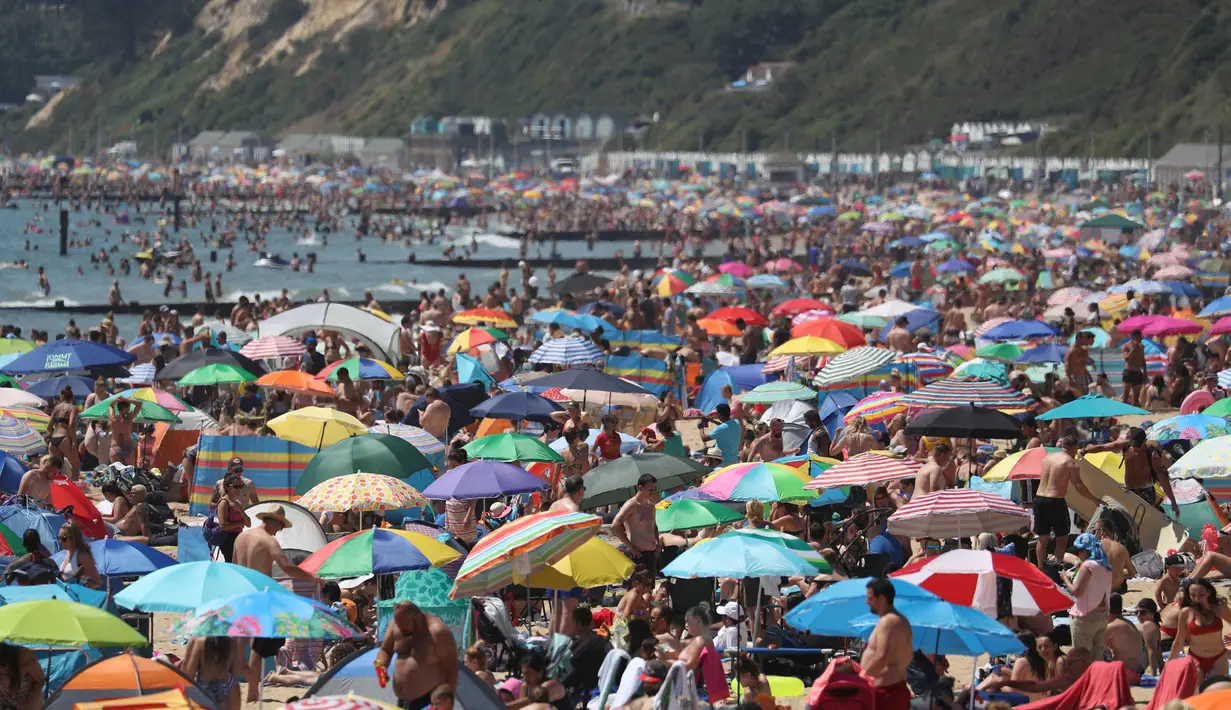 Kerumunan pengunjung berkumpul di pantai untuk menikmati hari terpanas tahun ini di Bournemouth, Kamis (25/6/2020). Para pejabat di Inggris selatan menyatakan keadaan darurat setelah ribuan orang berbondong-bondong menyambangi pantai setempat. (Andrew Matthews/PA via AP)