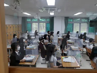 Siswa menunggu kelas dimulai dengan pembatas plastik di atas meja di Jeonmin High School di Daejeon, Korea Selatan, Rabu (20/5/2020). Korea Selatan akhirnya membuka kembali kegiatan belajar di kelas untuk siswa menengah atas setelah sempat tertunda hingga lima kali. (Kim Jun-beom/Yonhap via AP)