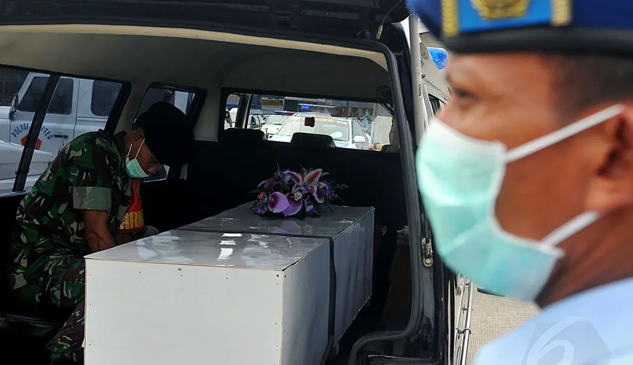 Tim SAR gabungan kembali menerima 12 jenazah korban pesawat AirAsia QZ8501 di Lanud TNI AL Juanda, Surabaya, Sabtu (3/1/2015). Tampak, salah satu anggota TNI menjaga peti jenazah korban pesawat AirAsia QZ8501. (Liputan6.com/Johan Tallo)