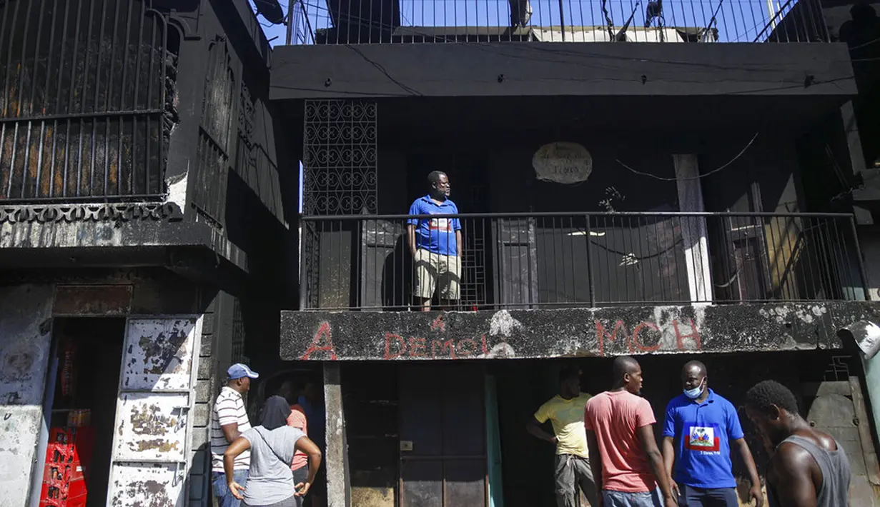 Warga berdiri di rumah mereka yang rusak usai ledakan truk pengangkut BBM di Cap-Haitien, Haiti, 14 Desember 2021. Truk tersebut diduga terbalik setelah pengemudi kehilangan kendali saat membelok untuk menghindari ojek. (AP Photo/Joseph Odelyn)