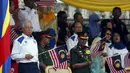 PM Najib Razak (kiri) mengibarkan bendera nasional Malaysia saat merayakan Hari Kemerdekaan ke-58 di Kuala Lumpur, Senin (31/8/2015).  Perayaan kemerdekaan kali ini dilakukan di tengah desakan mundur kepada PM Najib. (REUTERS/Olivia Harris)