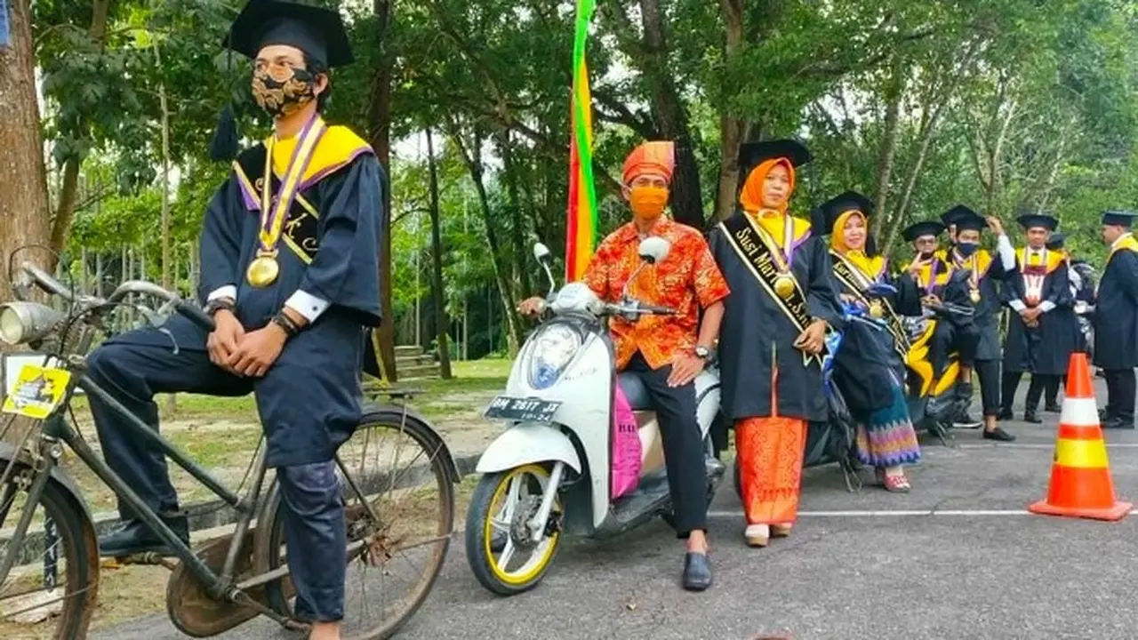 Seorang mahasiswa Universitas Lancang Kuning memakai sepeda ontel untu wisuda drive thru.