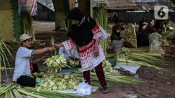 Pedagang musiman melayani pembeli kulit ketupat di bawah kolong jembatan kawasan Pesanggrahan, Jakarta, Jumat (8/7/2022). Pedagang musiman memanfaatkan Idul Adha untuk berjualan kulit ketupat. (Liputan6.com/Johan Tallo)