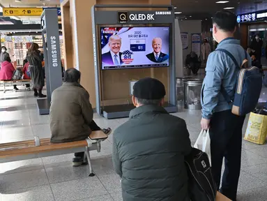 Orang-orang menonton program berita televisi tentang pemilihan presiden (pilpres) AS yang menampilkan gambar Presiden Donald Trump (kiri) dan calon presiden dari Partai Demokrat Joe Biden (kanan), di sebuah stasiun kereta api di Seoul, Korea Selatan pada Rabu (4/11/2020). (Photo by Jung Yeon-je / AF