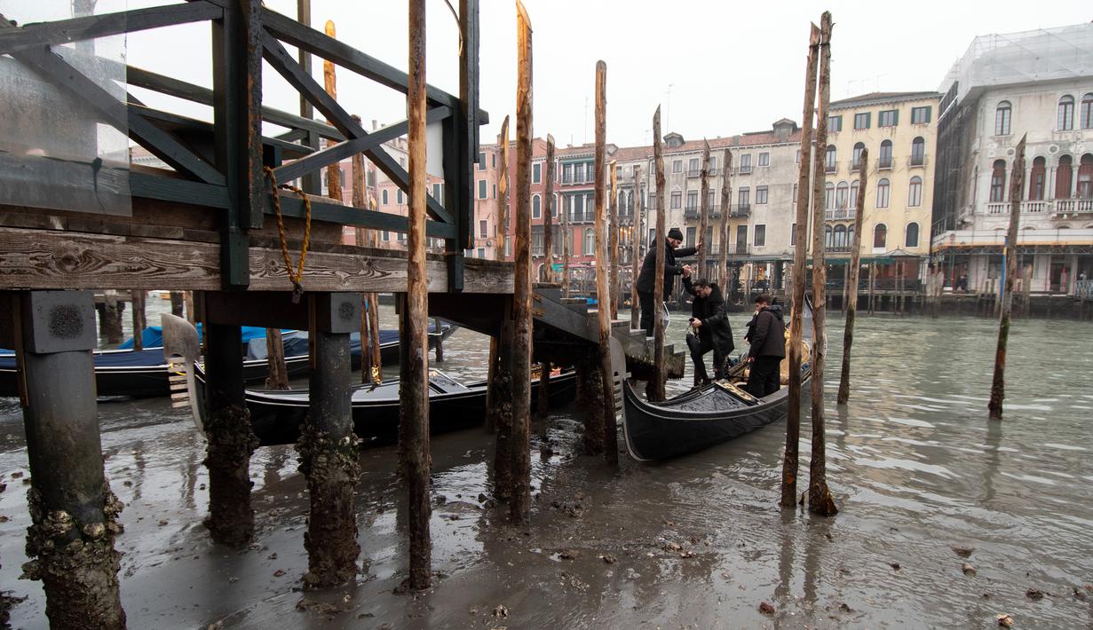 <p>Penumpang turun dari gondola yang berlabuh di sepanjang kanal saat air surut di Venesia, Italia, 21 Februari 2023. Beberapa kanal sekunder Venesia praktis mengering akhir-akhir ini akibat gelombang surut terkait dengan sistem cuaca bertekanan tinggi yang berkepanjangan. (AP Photo/Luigi Costantini)</p>