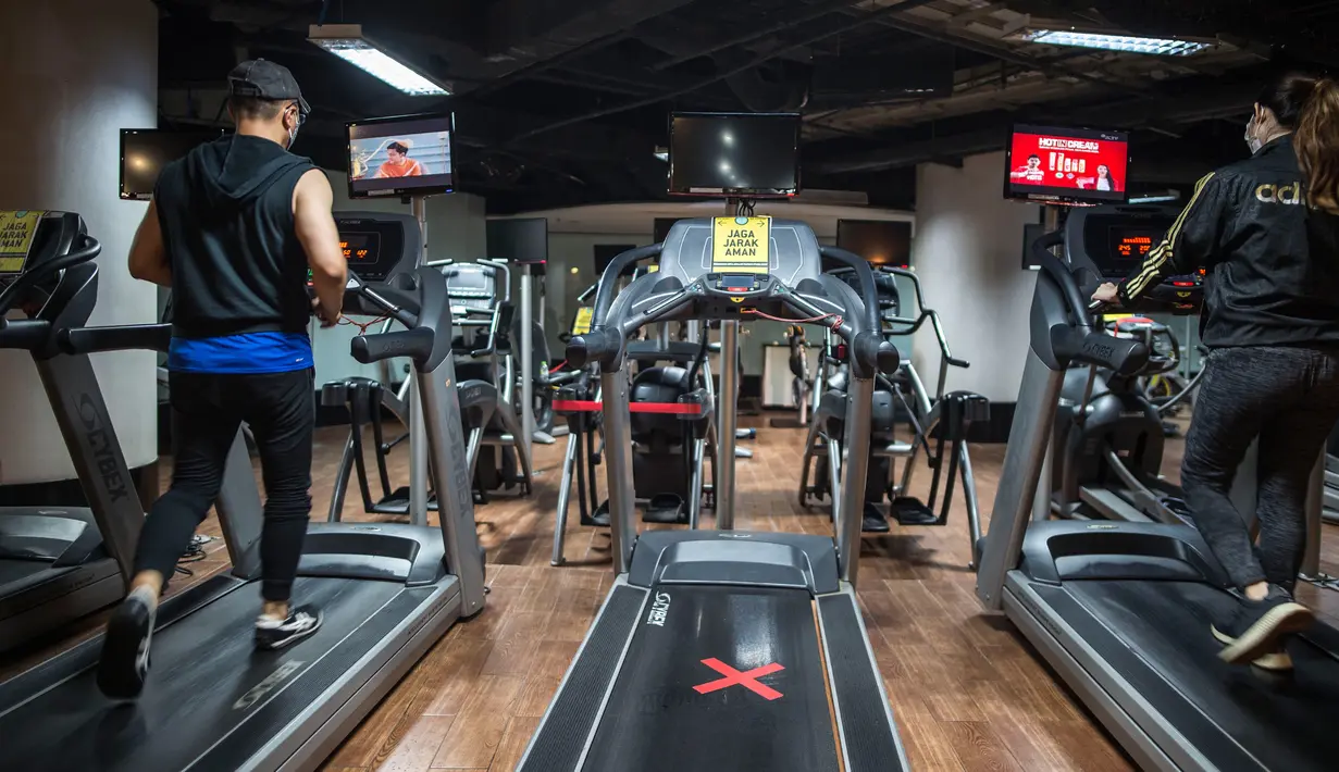 Orang-orang berolahraga di sebuah tempat gym yang menerapkan jarak fisik di Surabaya, Rabu (21/10/2020). Pusat kebugaran itu dibuka dengan menerapkan protokol kesehatan sebagai pencegahan COVID-19. (Juni Kriswanto / AFP)