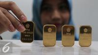 Petugas menunjukan emas batangan di kantor BNI Syariah, Jakarta, Senin (30/11). Harga jual-beli kembali (buyback) emas Antam turun Rp 1.000 usai akhir pekan kemarin naik di tengah turunnya harga emas global. (Liputan6.com/Angga Yuniar)