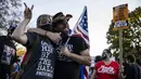 Seorang pendukung Presiden Donald Trump (kanan) dan seorang pendukung mantan Wakil Presiden Joe Biden berfoto bersama saat yang lain merayakan hasil Pilpres Amerika Serikat di Black Lives Matter Plaza, dekat Gedung Putih di Washington pada Minggu (8/11/2020). (Samuel Corum/Getty Images/AFP)