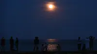 Warga mengamati keindahan supermoon yang terlihat di atas Pantai Sanur, Bali, Senin (14/11). Fenomena ini terjadi saat bulan mencapai titik terdekat dengan bumi dan merupakan fenomena supermoon terbesar dalam 68 tahun terakhir. (SONNY TUMBELAKA/AFP)