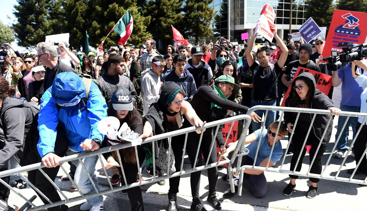 Demonstran berusaha menerobos pembatas dan mencoba masuk hotel saat menggelar aksi menolak Donald Trump di Burlingame, California (29/4). aksi ini digelar depan Hotel Hyatt, lokasi Donald Trump melakukan kampanye Pilpres AS. (REUTERS/Noah Berger)