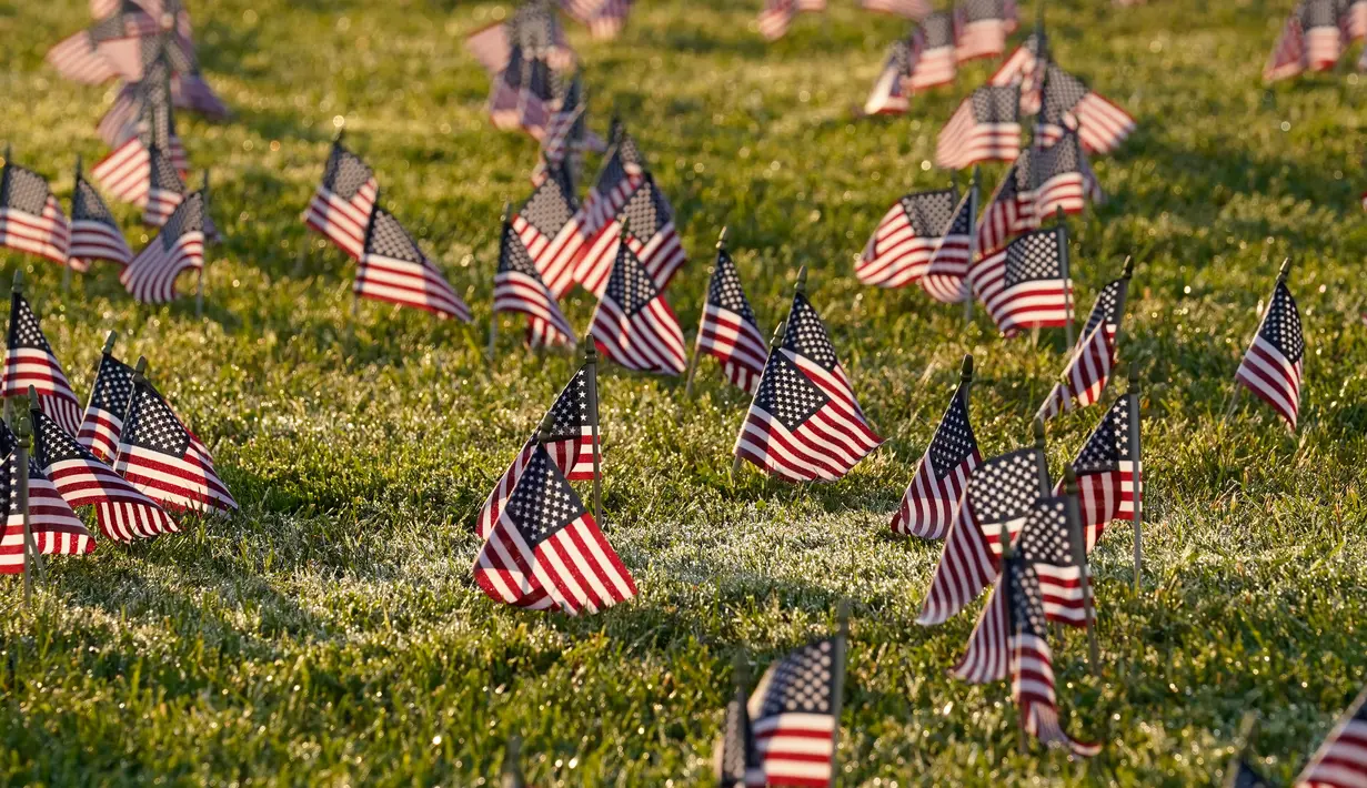 Aktivis dari COVID Memorial Project meletakkan ribuan bendera Amerika berukuran kecil di di halaman National Mall di Washington, Selasa (22/9/2020). Ribuan bendera itu menandai 200 ribu nyawa yang hilang akibat virus corona Covid-19 di Amerika Serikat. (AP Photo/J. Scott Applewhite)