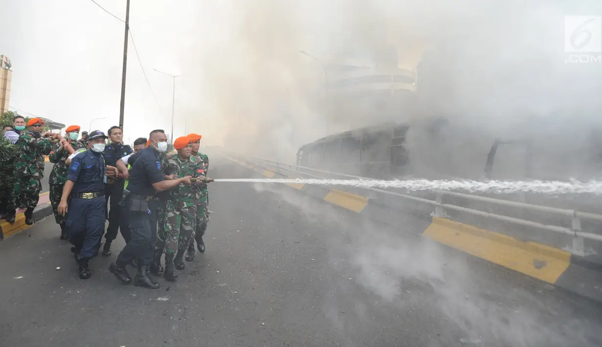 Sejumlah anggota TNI memadamkan api yang membakar dua unit bus polisi di dekat Flyover Slipi, Palmerah, Jakarta Barat, Rabu (22/5/2019). Anggota terus berusaha melakukan pendinginan mengunakan APAR agar api tak kembali menyala. (merdeka.com/Arie Basuki)