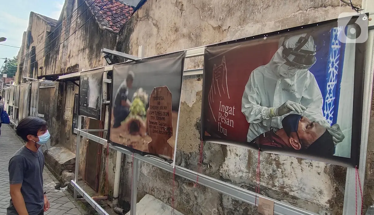 Warga melihat pameran foto jurnalistik karya pewarta foto Indonesia Tangerang di kawasan Pasar Lama, Tangerang, Minggu (30/5/2021). Pameran foto bertajuk meredanya Covid-19 ini bertujuan agar masyarakat dapat mengenal bahaya Covid-19 yang tengah mewabah di Indonesia.  (Liputan6.com/Angga Yuniar)