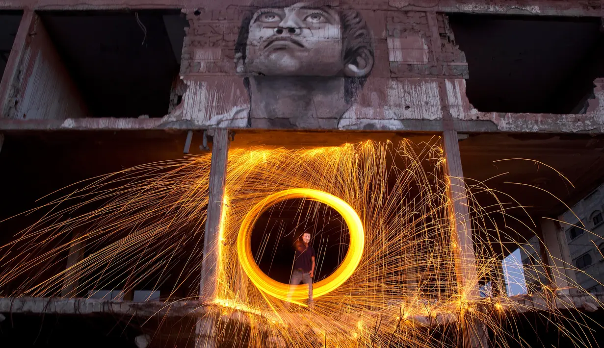 Seorang pria bermain kembang api di atas reruntuhan selama bulan suci Ramadan 1440 H di Kota Gaza, Palestina (13/5/2019). (AP Photo/Hatem Moussa)