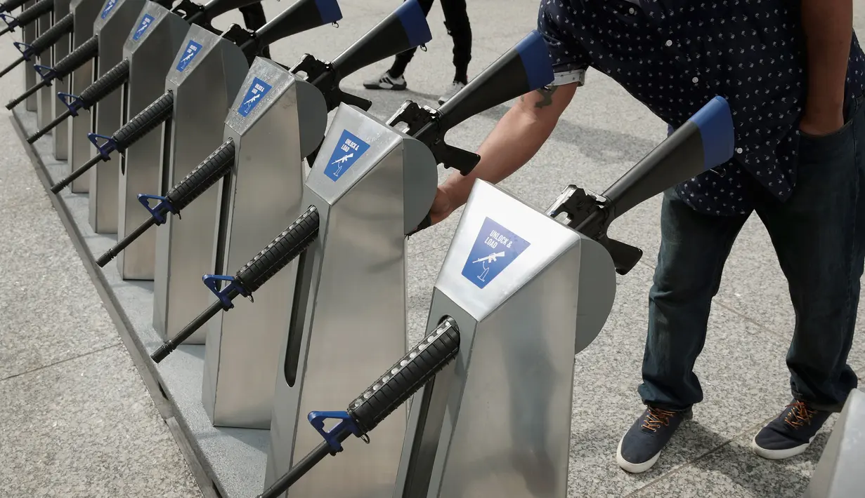 Seorang pria memegang senjata api yang merupakan instalasi seni dari Program Chicago Gun Share di Daley Center Plaza, Chicago, Illinois (14/5). (Scott Olson / Getty Images / AFP)