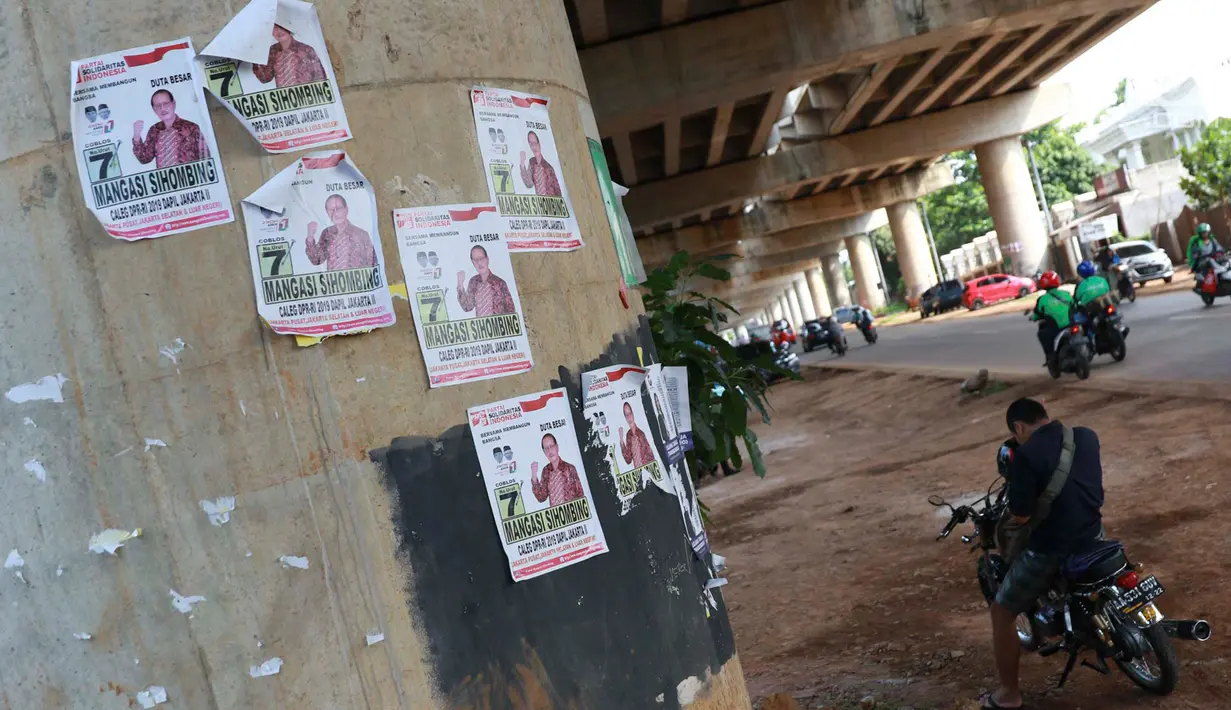 Pengendara berhenti di dekat alat peraga kampanye calon legislatif yang menempel di sepanjang tiang penyangga Jalan Tol Desari, Jakarta, Kamis (25/4). Meskipun Pemilu serentak telah selesai, namun masih banyak APK di sejumlah sudut Ibu Kota dan menjadi sampah visual. (Liputan6.com/Immanuel Antonius)