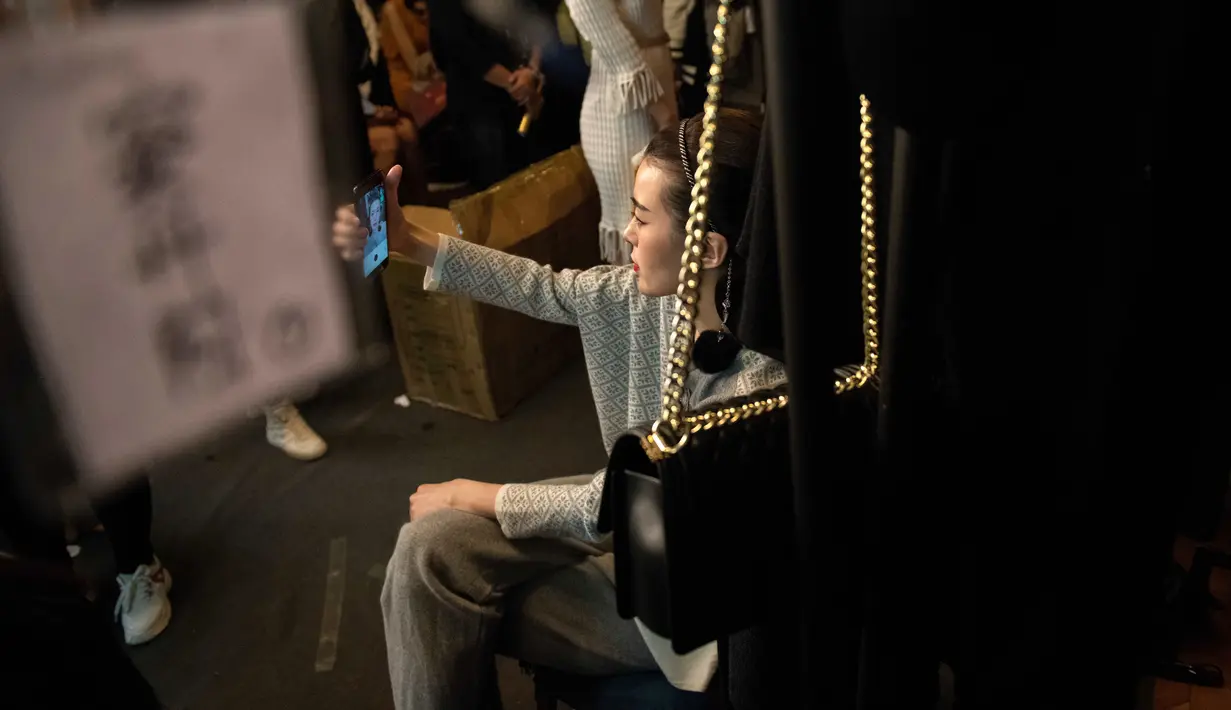 Seorang model berselfie di belakang panggung sebelum tampil membawakan koleksi Rabbit-Warm karya Zhuang Ganran selama China Fashion Week di Beijing (30/10). (AFP Photo/Nicolas Asfouri)