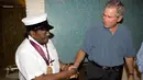 Foto yang diambil pada 29 Agustus 2006 menunjukkan musisi Fats Domino (kiri) mengenakan mendali bersalaman dengan Presiden AS saat itu, George W. Bush. Setelah berita kepergian Fats Domino beredar, musisi dunia pun ikut berduka. (AFP Photo/Eric Daper)