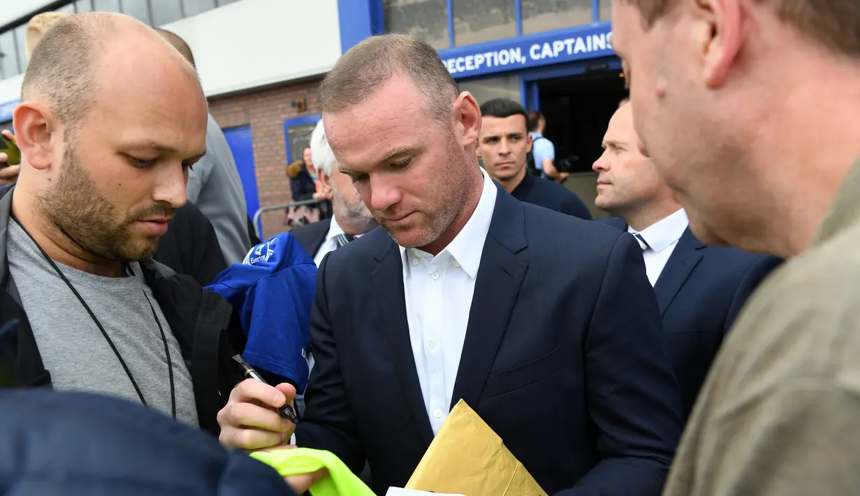 Penyerang baru Everton Wayne Rooney, memberikan tanda tangan pada penggemarnya saat konferensi pers di Goodison Park di Liverpool (10/8). (AFP Photo/Paul Ellis)