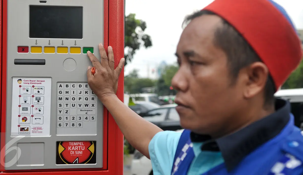 Juru parkir berada di dekat mesin terminal parkir elektronik (TPE) di Jalan Ir H Juanda, Jakarta, Senin (24/10). Pemprov DKI resmi menerapkan sistem pembayaran parkir pinggir jalan (on street) dengan TPE. (Liputan6.com/Yoppy Renato)