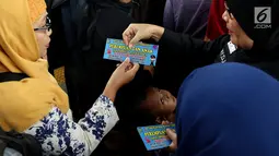 Petugas dari Polda Metro Jaya membagikan stiker kepada pengguna Kereta di Stasiun Tanah Abang, Jakarta, Kamis (21/12). Stiker ini bertuliskan informasi tentang pengaduan ketika terjadi kasus pelecehan seksual di ruang publik. (Liputan6.com/JohanTallo)