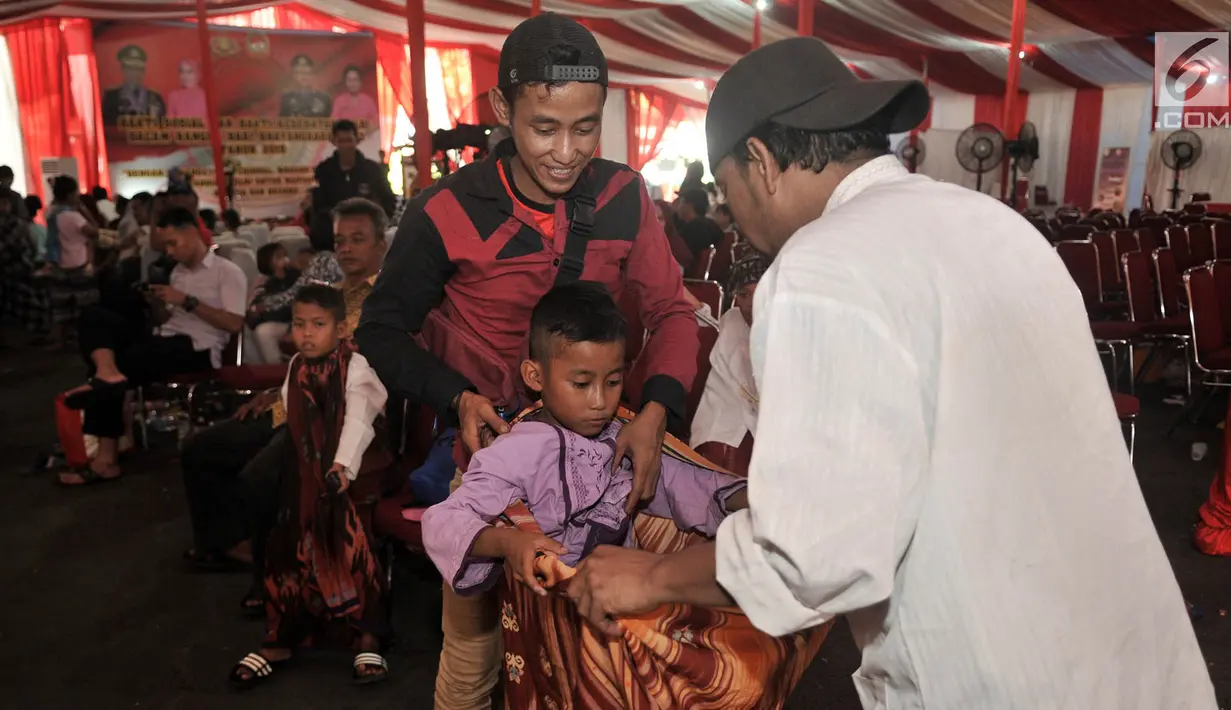 Seorang anak memakai sarung saat mengikuti sunatan massal gratis dalam acara Bakti Sosial dan Kesehatan Polri di Mapolsek Ciracas, Jakarta, Kamis (4/7/2019). Selain sunatan massal gratis, acara ini juga diisi dengan pengobatan dan cek kesehatan gratis. (merdeka.com/Iqbal Nugroho)
