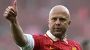 Pelatih Liverpool, Arne Slot mengacungkan jempolnya saat melakukan selebrasi setelah timnya dipastikan menyabet gelar juara Liga Inggris 2024/2025 setelah mengalahkan Tottenham Hotspur di Anfield, Liverpool, Inggris, Minggu (27/04/2025). (AFP/Paul Ellis)