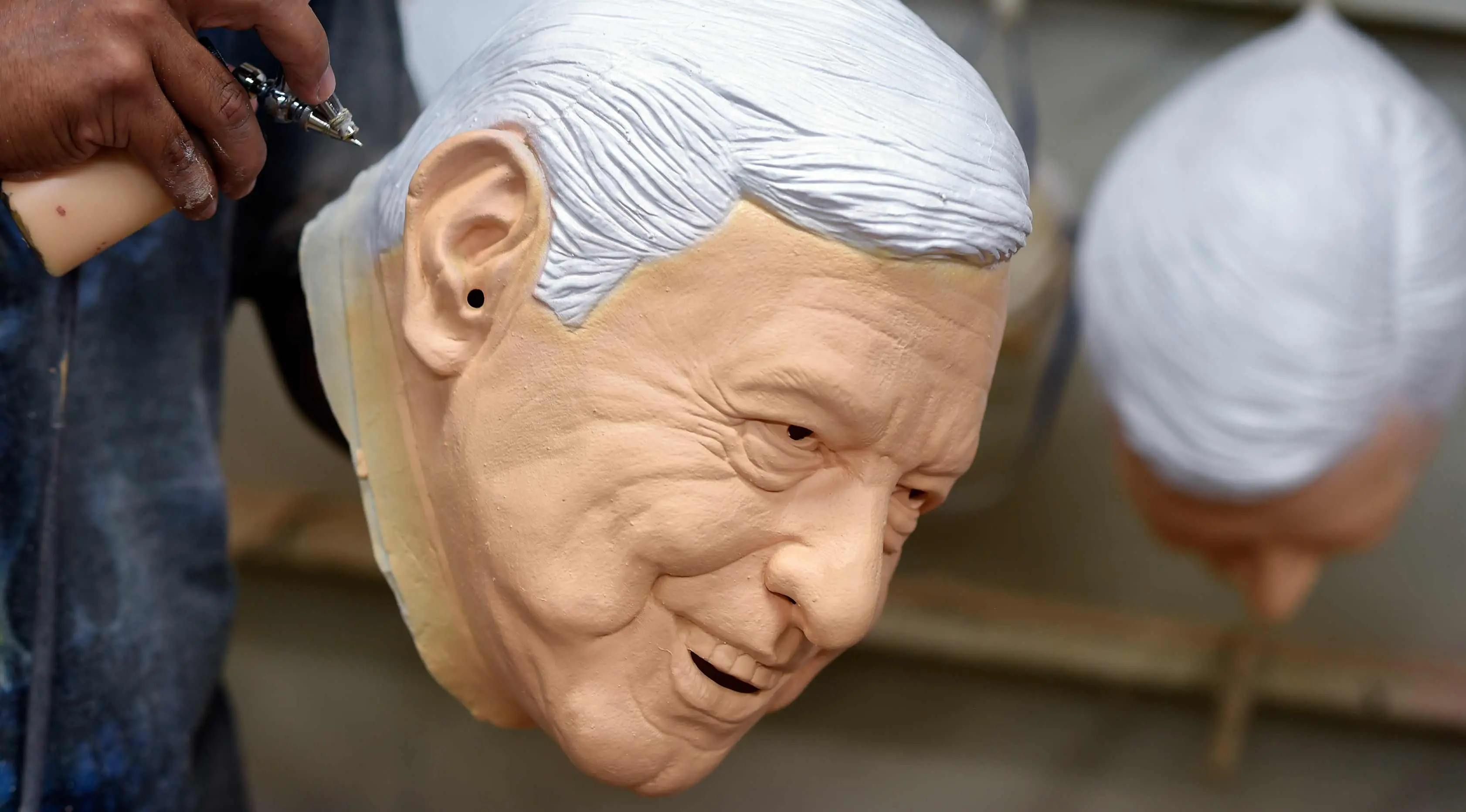 Pekerja memberikan sentuhan akhir pada topeng lateks dari calon presiden Meksiko Andres Manuel Lopez Obrador, dari partai MORENA, di Rev, sebuah pabrik di Cuernavaca, Morelos State, Meksiko, (28/3). (AFP Photo/Alfredo Estrella)