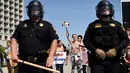 Petugas berjaga saat sejumlah wanita bertelanjang dada menolak Donald Trump di Burlingame, California (29/4). Demonstran menggelar aksi di depan Hotel Hyatt, lokasi Donald Trump melakukan kampanye Pilpres AS. (REUTERS/Noah Berger)