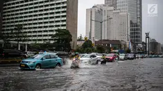Sejumlah kendaraan melintas menerjang genangan air di kawasan Bunderan HI, Jakarta, Kamis (22/11). Genangan air hujan setinggi 40 cm tersebut disebabkan hujan deras yang melanda Jakarta pada siang hari. (Liputan6.com/Faizal Fanani)