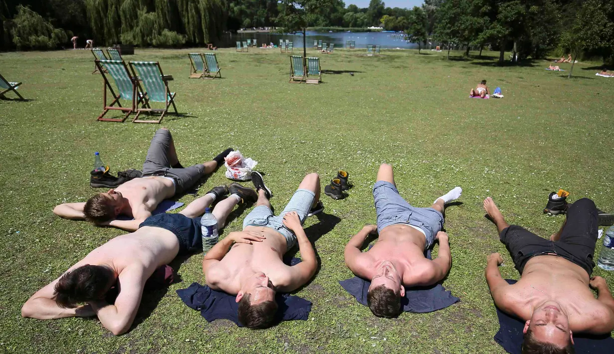 Sejumlah pria berjemur di Regents Park, London, Inggris, Selasa (19/7). Cuaca panas yang melanda Inggris dimanfaatkan warga untuk berjemur. (REUTERS/Neil Hall)