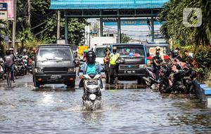Kendaraan bermotor melintasi jalan yang tergenang air rob (banjir pasang air laut) di Kawasan Pasar Ikan Muara Baru, Jakarta, Kamis (4/6/2020). Banjir rob di Pelabuhan Muara Baru tersebut terjadi akibat cuaca ekstrem serta pasangnya air laut. (Liputan6.com/Faizal Fanani)