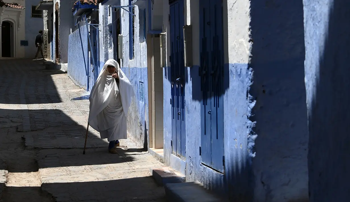 Seorang wanita berjalan di sepanjang gang kecil, Kota Chefchaouen, Maroko, Minggu (1/5). Keindahan kota Chefchaouen bahkan mengalahkan keindahan kota penuh cinta, Paris. (FADEL SENNA / AFP)