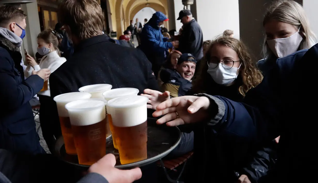 Orang-orang mengantre untuk minum bir di teras restoran di Praha, Republik Ceko, Senin, (11/5/2020). Bar, restoran, kafe yang menawarkan tempat duduk terbuka mulai melayani konsumen pertama mereka sejak 14 Maret. (AP/Petr David Josek)