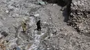 Seorang wanita menyebrangi sungai setelah jalanan rusak akibat banjir bandang di Ursoon, daerah terpencil Chitral di Pakistan utara, Minggu (3/7). Banjir merusak sejumlah rumah dan sebuah masjid dengan jumlah korban tewas 43 orang (GUL HAMAAD Farooqi/AFP)