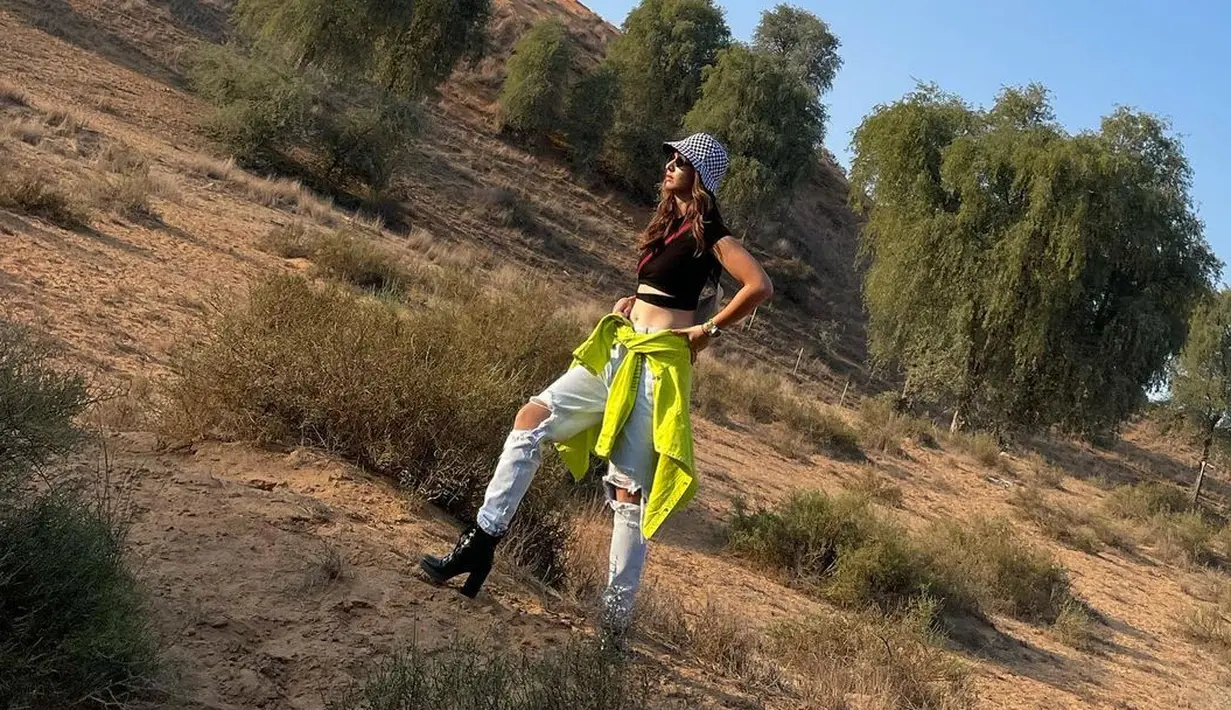 Nia Ramadhani tampil mengenakan bucket hat bermotif garis bernuansa monokrom. Kali ini ia memadukannya dengan busana kasual, yaitu crop top hitam dengan celana denim, dan jaket yang diikatkan di pinggangnya, serta kacamata hitam. Foto: Instagram.