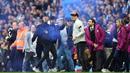Fans menyalakan smoke bomb saat turun ke lapangan usai laga Manchester City melawan Swansea City pada lanjutan Premier League di Etihad Stadium, Manchester, (22/4/2018). Manchester City menang 5-0. (AFP/Paul Ellis)