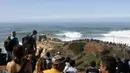Orang-orang berkumpul di sepanjang puncak tebing untuk menyaksikan sesi selancar derek di Praia do Norte atau Pantai Utara di Nazare, Portugal, Kamis (29/10/2020). (AP Photo/Pedro Rocha)