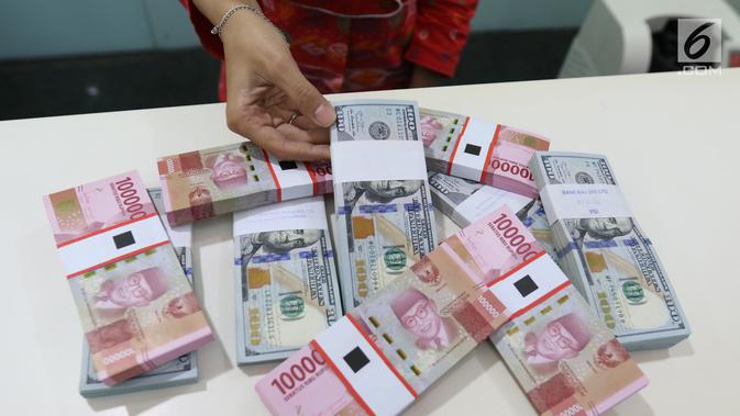 Teller menunjukkan mata uang rupiah dan dolar di Bank Mandiri, Jakarta, Kamis (10/1). Hingga hari ini, US$ 1 dibanderol Rp 14.020. Rupiah menguat 0,71% dibandingkan posisi penutupan perdagangan hari sebelumnya. (Liputan6.com/Angga Yuniar)