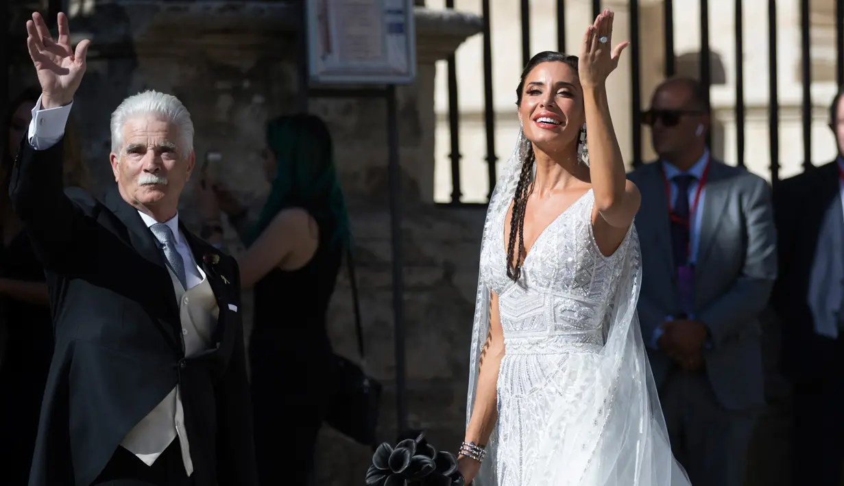 Model dan presenter Pilar Rubio bersama ayahnya menyapa awak media saat tiba di gereja dalam upacara pernikahannya di Katedral Seville, Spanyol (15/6/2019). Sergio Ramos dan Pilar Rubio telah memiliki tiga putra yaitu, Sergio, Marcos, dan Alejandro. (AP Photo/Antonio Pizarro)