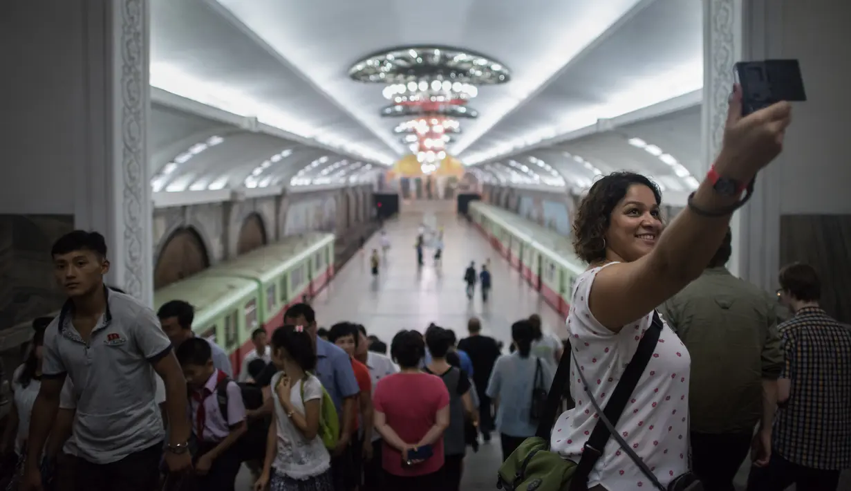 Foto pada 23 Juli 2017 terlihat turis berswafoto ketika mengunjungi sebuah stasiun kereta bawah tanah di Pyongyang, Korea Utara.  (Ed JONES/AFP)