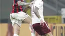 Bek AC Milan, Alessio Romagnoli melompat saat berebut bola dengan penyerang Torino, Simone Zaza pada babak 16 besar Coppa Italia 2020/2021 di San Siro, Rabu (13/1/2021) dini hari WIB. Laga terkunci 0-0, AC Milan menang 5-4 atas Torino di babak adu penalti. (AP Photo/Antonio Calanni)