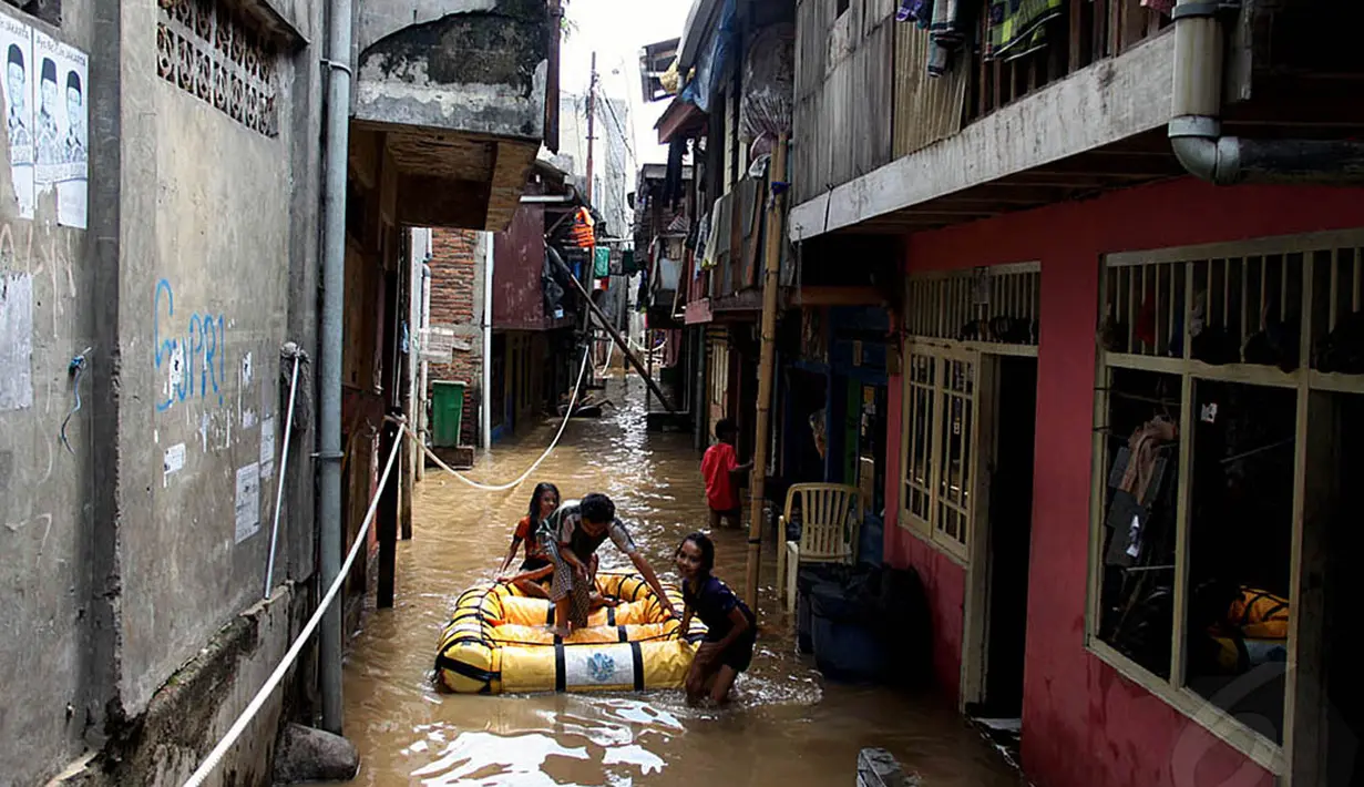 Warga menggunakan perahu karet saat melintasi genangan banjir di kawasan Kampung Pulo, Jakarta, Kamis (13/11/2014). (Liputan6.com/Johan Tallo) 