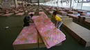 Sukarelawan menyiapkan tempat tidur rumah sakit lapangan dalam gedung kargo di Bandara Internasional Don Mueang, Bangkok, Thailand, Kamis (29/7/2021). Rumah sakit lapangan didirikan setelah Bangkok kehabisan tempat tidur rumah sakit untuk ribuan pasien. (AP Photo/Sakchai Lalit)
